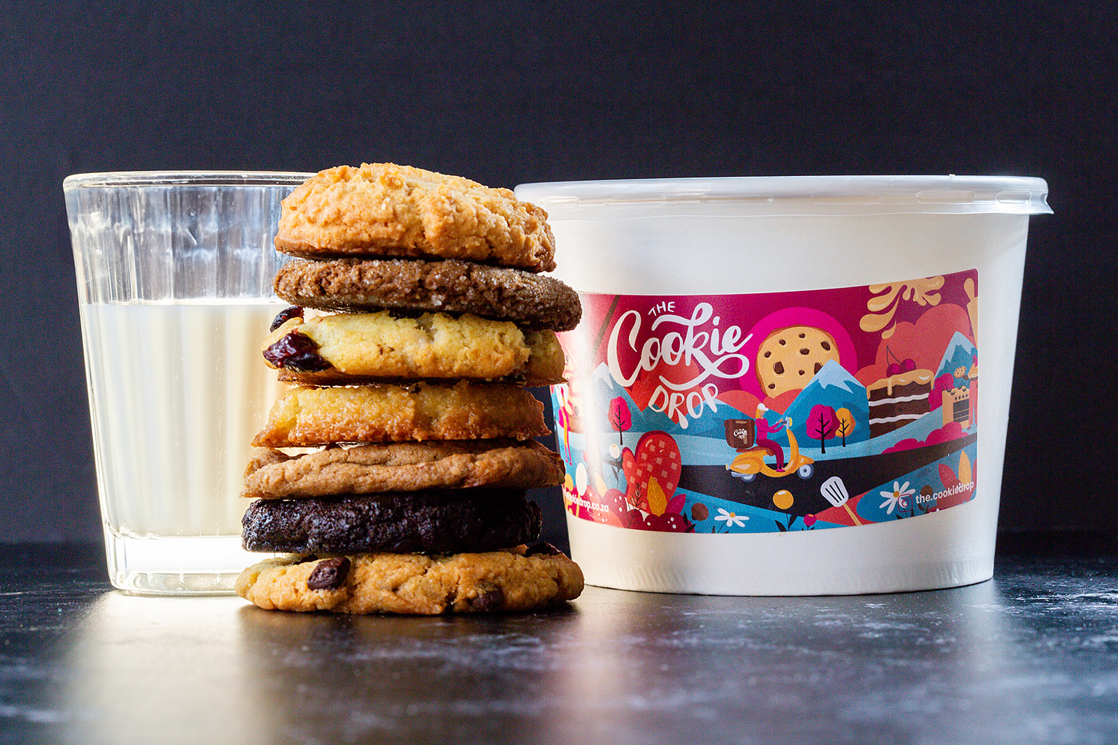 Stack of warm chocolate chip cookies beside a glass of milk